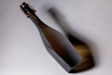 Unlabeled bottle of sparkling wine, with swing top closure, on grey background.