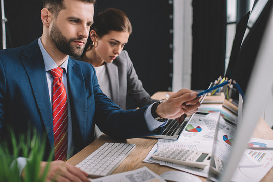 Selective focus of information security analysts identifying problems while working with computers and charts in office