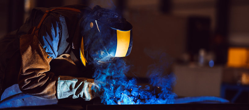 Industrial Welder With Torch and Protective Helmet