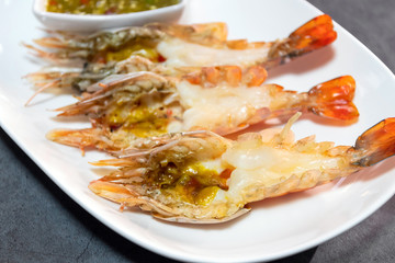Fototapeta na wymiar Charcoal grilled river prawns served with spicy seafood sauce on porcelain plate