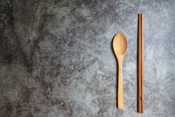 Wooden spoon and chopstick isolated on grey vintage background with copy space.