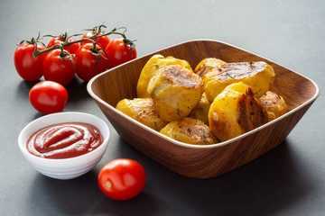 Spicy baked with spices fried potatoes with tomatoes and sauce on the table.