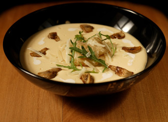 plate with cream soup with mushrooms on table wood background