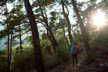 Obraz premium A girl with a backpack goes along a mountain trail.