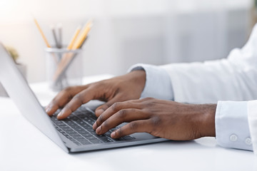 Close up of black doctor hands typing on laptop