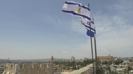 JERUSALEM, ISRAEL - MAY 18, 2016: The silhouette logo of the Tower of David Museum, the Israeli flag and the Jerusalem city flag on the Tower of David
