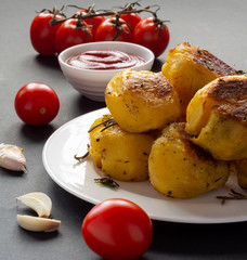 Spicy baked with spices fried potatoes with tomatoes and sauce on the table.