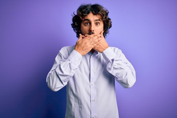 Young handsome business man with beard wearing shirt standing over purple background shocked covering mouth with hands for mistake. Secret concept.