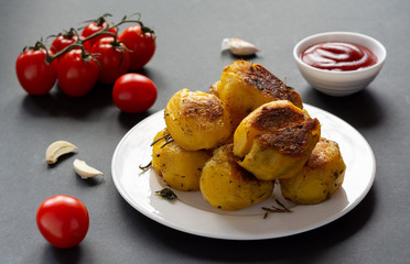 Spicy baked with spices fried potatoes with tomatoes and sauce on the table.