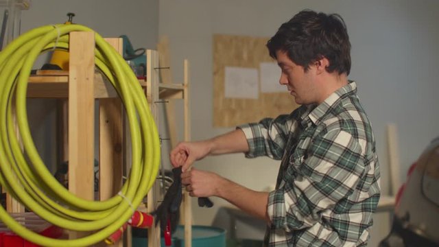 Guy puts on gloves to tidy up in the garage