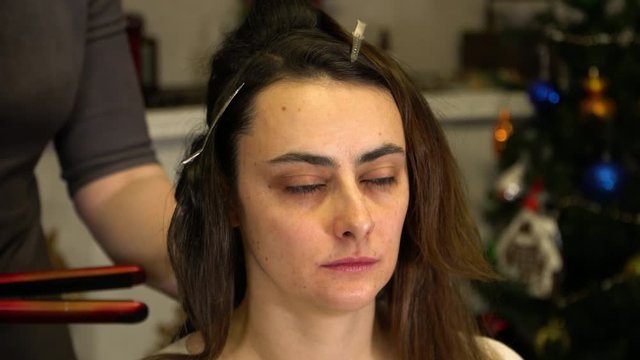 The stylist uses a Curling iron and works with the hair