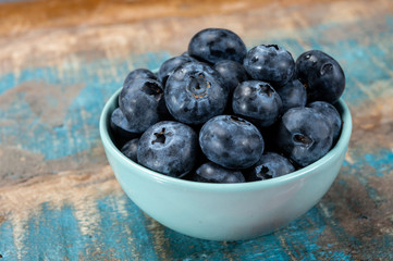 Fresh ripe blueberries in bowl on wooden background