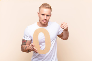 young blonde man angry, anger, disagreement, holding a number 0.