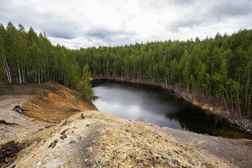 Flooded copper pyrite open pit quarry with brown water lake