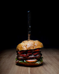 Spotlight of a gourmet burger with a knife with black background