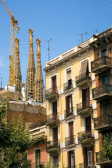 Obraz premium Apartments in foreground with view of Sagrada Familia Holy Family Church by architect Antoni Gaudi, Barcelona, Spain begun in 1882 and continuing to be built into the 21st Century