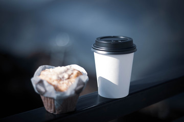 Coffee in a disposable white glass with a black lid and a delicious cupcake. - obrazy, fototapety, plakaty