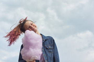 Beautiful smiling teenage girl with pink hair, hairstyle holding candy floss