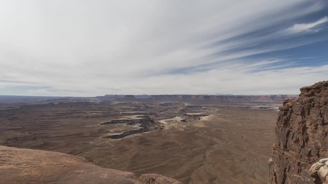A wide timelapse lookout out from Green River Overlook at Canyonlands National Park towards the Green River canyon far below. Clouds flow overhead.