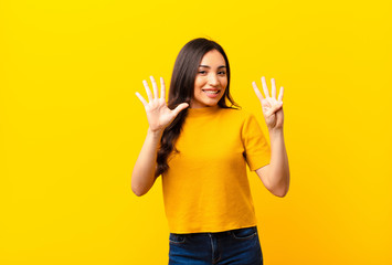 young latin pretty woman smiling and looking friendly, showing number nine or ninth with hand...