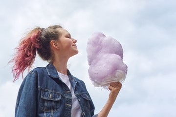 Beautiful smiling teenage girl with pink hair, hairstyle holding candy floss