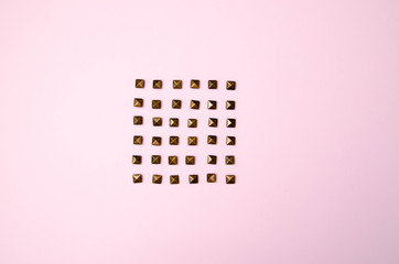 Metal rivets on pink glamourous background. Sample of stylish clothing products. Textured...