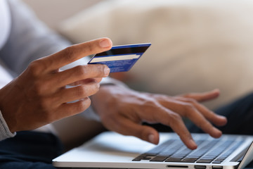 Close up of black girl hold bank credit card and type on laptop, shopping online using computer,...