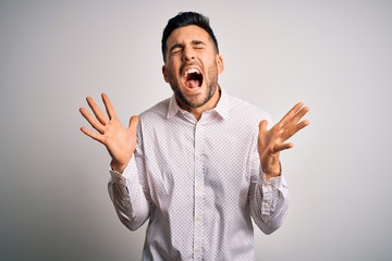 Fototapeta premium Young handsome man wearing elegant shirt standing over isolated white background celebrating mad and crazy for success with arms raised and closed eyes screaming excited. Winner concept