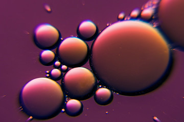 Purple oil bubbles in a liquid. Beautiful structure of oil and water in macro as abstract background.
