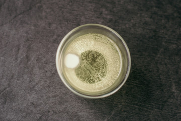 Effervescent vitamin c tablet in a glass goblet on a gray stone background. Prevention of flu and colds, strengthening immunity against viruses