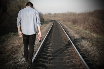 Man with alcohol on railway tracks outdoors. Depression disease. Economy crisis, poverty, unemployment concept. Consequences of coronavirus people isolation during quarantine. Hopelessness.