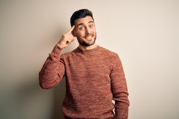 Fototapeta premium Young handsome man wearing casual sweater standing over isolated white background Smiling pointing to head with one finger, great idea or thought, good memory