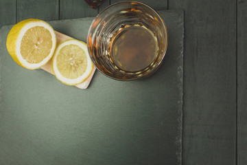 Whiskey and lemon on a black wooden background
