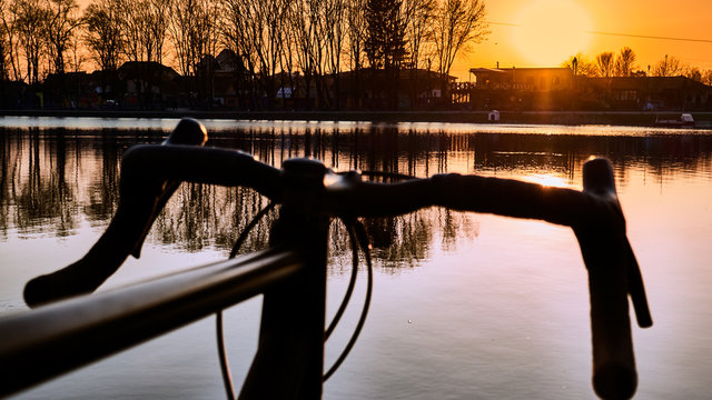 bicycle near lake, steering wheel over water on sunset background ,gravel bike close up