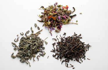 Dry leaves of black, green, and flower tea isolated on a white background, top view