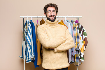 young cool berded man with clothes against flat wall