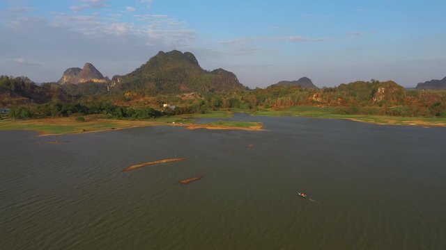 February 29th, 2020 - Perlis, Malaysia : 4k Establishing Aerial View of a boat cruising Timah Tasoh Lake side During Beautiful Sunset with Mountain view. Drone Moving Forward