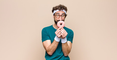 young sports man having a snack holding a pink sugar donut