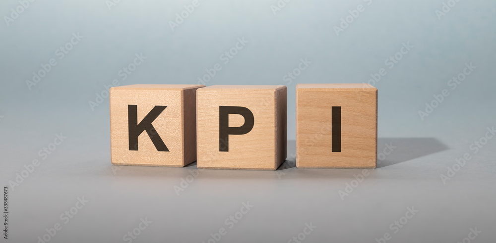 Poster acronym kpi - key performance indicator. wooden cubes with letters isolated on gray background