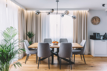 Dining room with wooden table and floor in modern apartment.