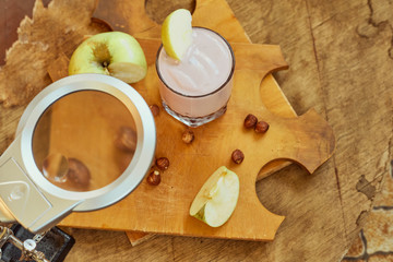 Yogurt with apple and nuts on a wooden background. Daylight.