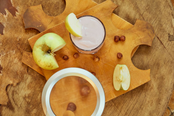 Yogurt with apple and nuts on a wooden background. Daylight.