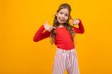 funny teenager girl in a red blouse and striped trousers shows herself on a yellow background with copy space