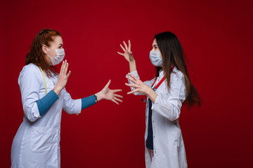 Two lovely young caucasian female in dark blue t-shirt, a white gown, white trousers with a...