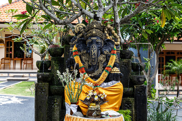Black Ganesha statue with a wreath of flowers.