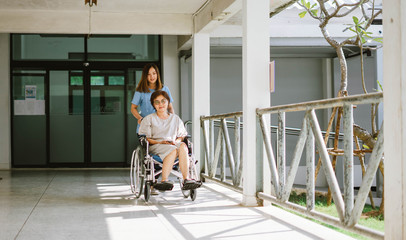 Smiling physiotherapist  taking care of the happy senior patient in wheelchair