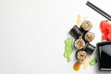 Delicious sushi rolls, sauces and chopsticks on white background, space for text