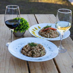 Two risotto dishes with white and red wine glasses