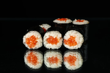 Delicious sushi rolls on black mirror background. Japanese food