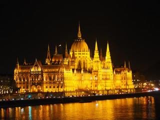 Obraz premium View of the Hungarian Parliament Building and the Danube river at night in Budapest, Hungary.